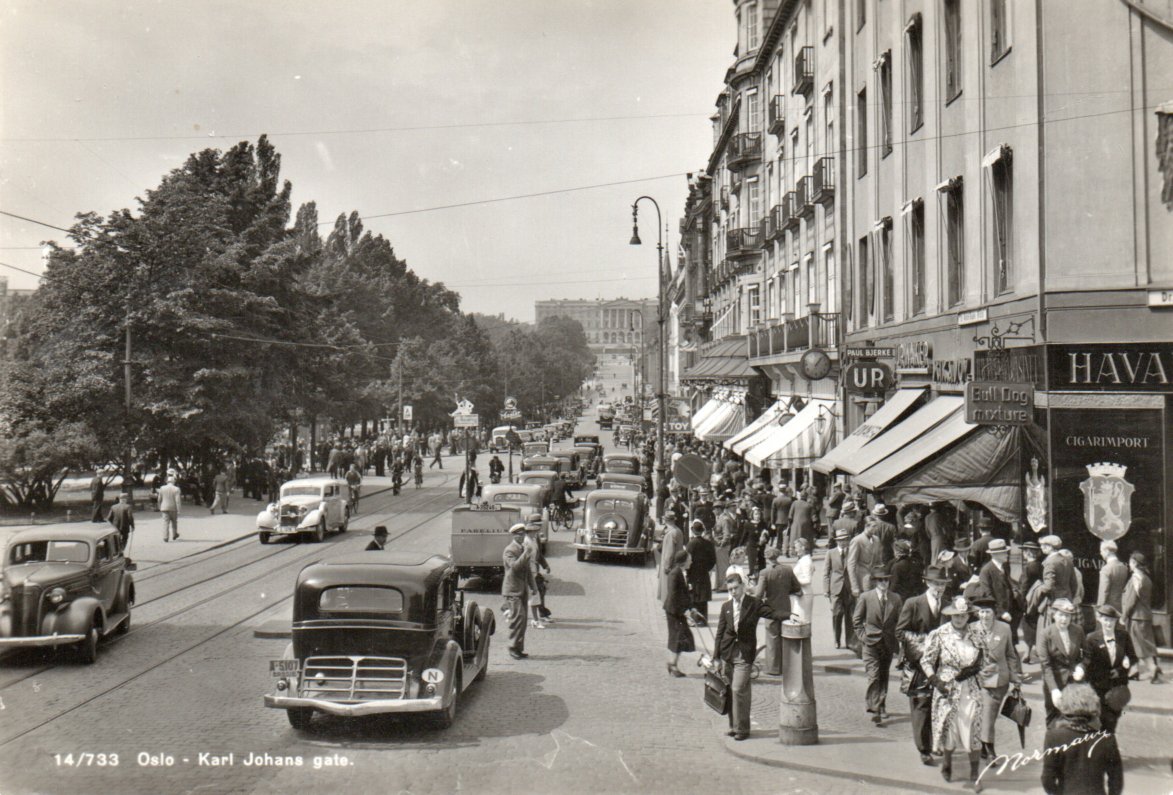 Karl Johans gate. Mange biler og mye folk på gaten.